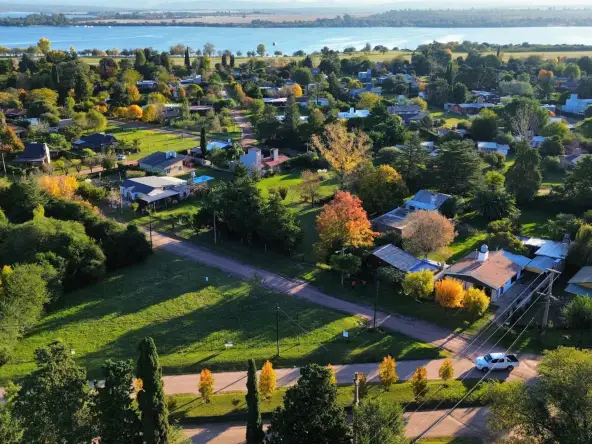 Vista aérea de la localidad de Villa Rumipal con el lago al fondo, calles de tierra, casas y el lote en primer plano