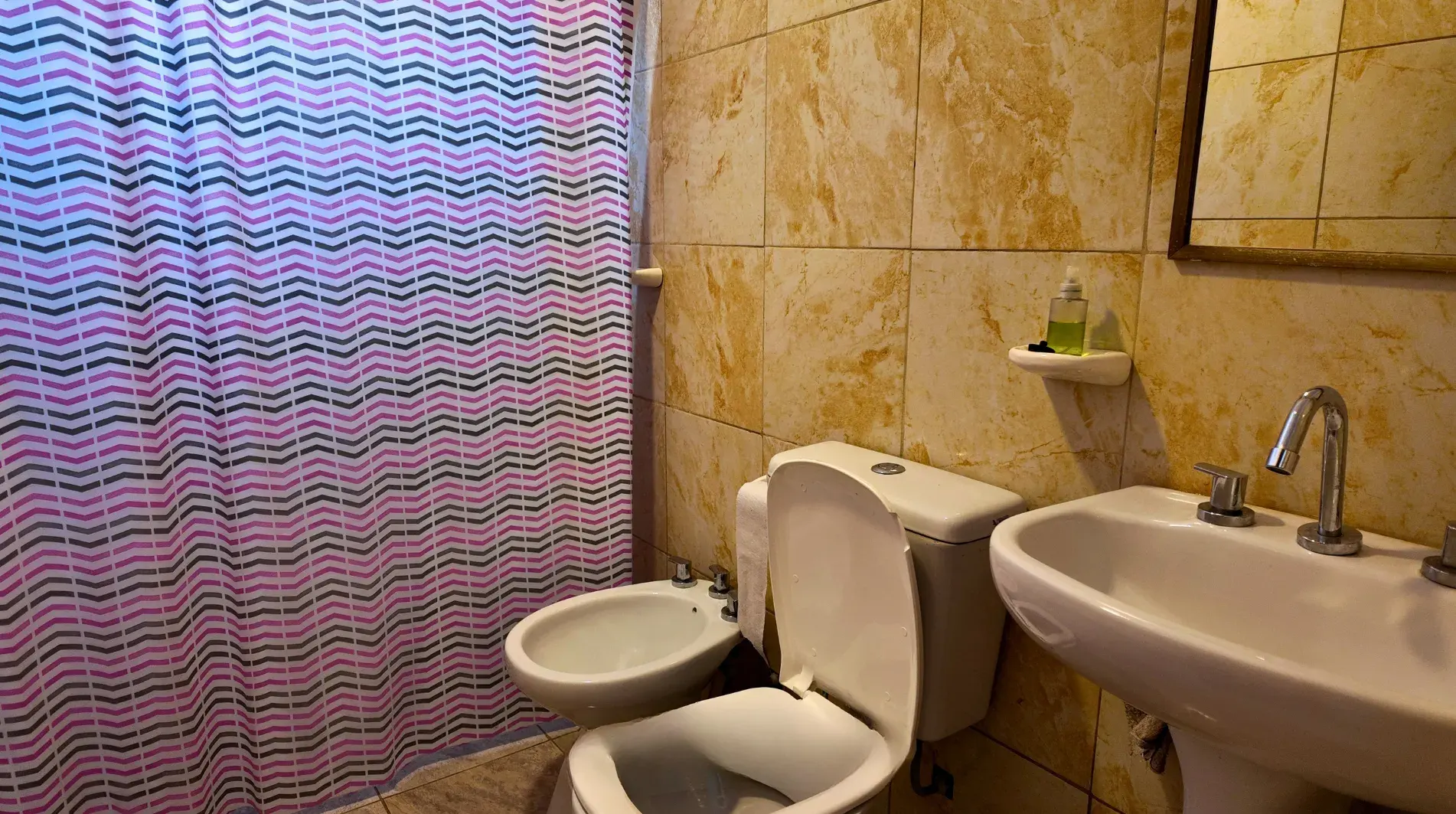 Baño completo con inodoro, bidet, lavatorio y ducha con cortina en departamento en alquiler en Villa del Dique