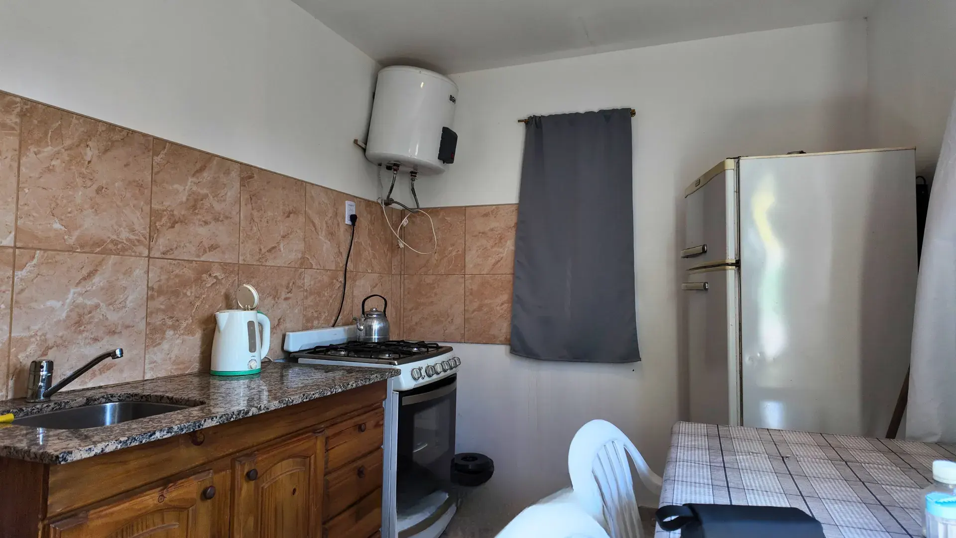 Cocina con mesada de granito, cocina a gas, termotanque y heladera en departamento en alquiler en Villa del Dique